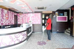 a man with a mop in a room at Hotel Sumi Palace in Thanjāvūr