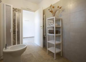 a bathroom with a sink and a toilet and a shelf at Agriturismo Casa Ricci in Magliano in Toscana