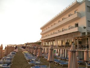 una fila di sedie a sdraio e ombrelloni di fronte a un hotel di Hotel Parrini a Follonica