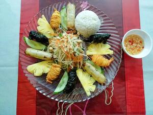 a plate of food with vegetables and rice on a table at Chez Loan Hotel in Ninh Binh