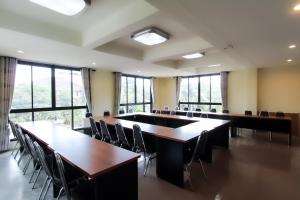 uma sala de conferências com mesas, cadeiras e janelas em Baan Pordeedin em Chiang Rai