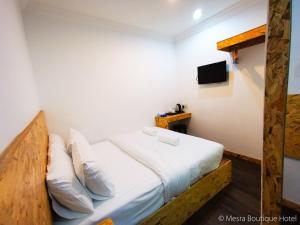 Schlafzimmer mit einem Bett mit weißer Bettwäsche und einem TV in der Unterkunft Mesra Boutique Hotel in Port Dickson