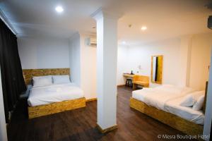 a bedroom with two beds and a table in it at Mesra Boutique Hotel in Port Dickson