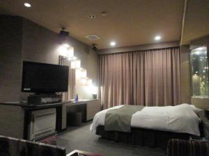 Schlafzimmer mit einem Bett und einem Flachbild-TV in der Unterkunft ウォーターゲート鹿児島 in Kagoshima