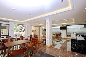 um restaurante com mesas, cadeiras e janelas em Luckful Hotel em Hanói