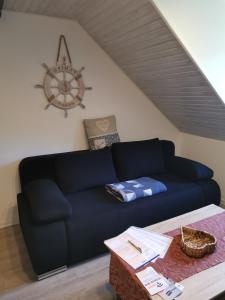 a blue couch in a living room with a clock at Susan's ole Schoolhus in Fehmarn
