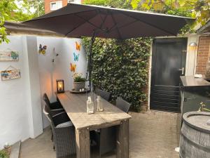 a wooden table with chairs and an umbrella on a patio at B&B Huize 't Goylaan in Utrecht
