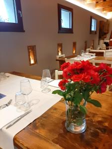 eine Vase roter Blumen auf einem Tisch in der Unterkunft Locanda Merlaschio in Faenza