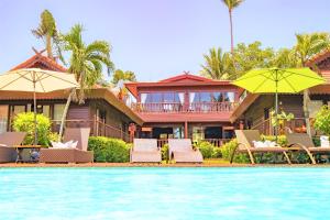 a house with chairs and umbrellas next to a swimming pool at Erawan Villa Hotel in Bang Rak Beach