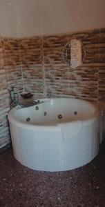 Casa Bella في Bolbaite: حوض استحمام أبيض في حمام بجدار من الطوب