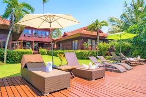 a deck with chairs and umbrellas in front of a house at Erawan Villa Hotel in Bangrak Beach