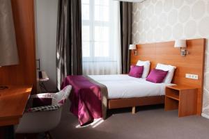 a hotel room with a bed with purple pillows at Hotel Kontakt der Kontinenten in Soesterberg