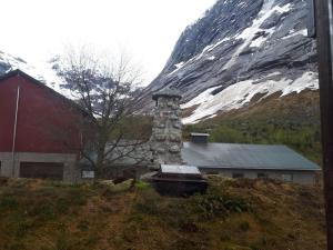a building with a stone chimney next to a mountain at Lunde Turiststasjon in Lunde