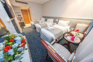 メッカにあるMontana Al Azizia Hotelのベッド2台、テーブル(花付)が備わる客室です。