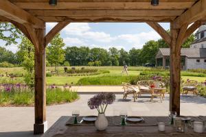 een houten pergola met een tafel en stoelen en een tuin bij Elvier B&B in Mol