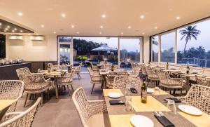 - un restaurant avec des tables, des chaises et de grandes fenêtres dans l'établissement The Acacia Morjim, à Morjim