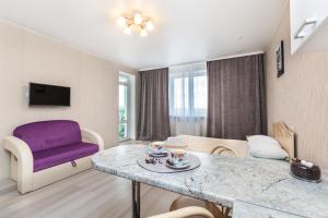 a living room with a table and a purple chair at Апартаменты Central Park на Таврической 9к1 in Tyumen