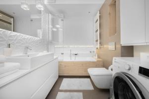 a white bathroom with a sink and a washing machine at INA Rent - Tre Mare Apartamenty in Gdańsk +138 photos