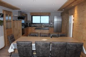 een keuken met een grote houten tafel en stoelen bij chalet bel horizon La Montagne Des Lamas in La Bresse