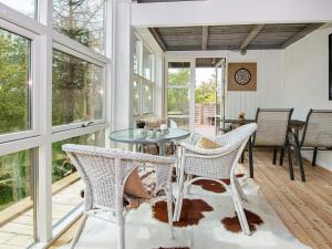 a screened in porch with a glass table and chairs at 6 person holiday home in Knebel in Knebel