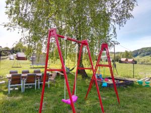 a red swing set in a park with a tree at Wakacyjne domki in Solina