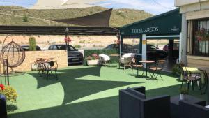 um pátio exterior com cadeiras e mesas e um stand de automóveis em Hotel Argos em Calasparra