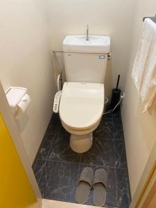 a bathroom with a toilet and a pair of slippers at Melody Heim 2C in Tokushima