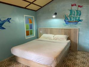1 dormitorio con 1 cama con una pintura en la pared en Heaven Beach Resort & Art, en Ko Phayam