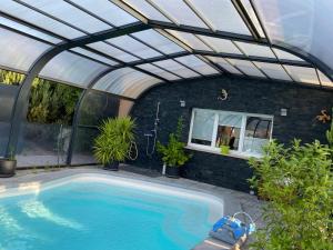 a swimming pool in a greenhouse with a roof at O Rendez Vous maison mitoyenne Piscine chauffée mars-octobre in Grimisuat