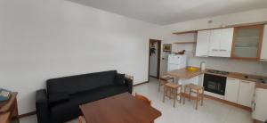 a living room with a black couch and a kitchen at Appartamento Raffaello in Cattolica
