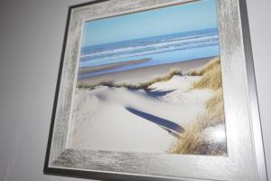 a picture of a beach in a frame on a wall at Appartement de standing in Berck-sur-Mer