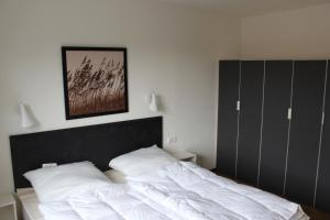 トラフェミュンデにあるDünenhaus Wohnung 10のベッドルーム(白いベッド、黒いヘッドボード付) +12枚の写真