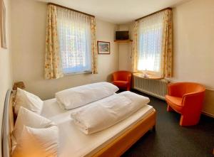 a bedroom with two beds and two chairs and two windows at Schwarzwaldgasthaus Linde in Tennenbronn