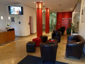 a lobby with black chairs and red columns in a building at Tagungshaus Reimlingen in Reimlingen