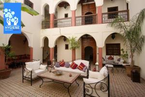 un edificio con un patio con sofás y una mesa en Riad petit Karmela, en Marrakech