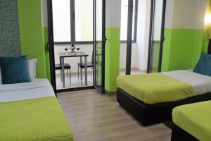 リスボンにあるユニベルソ ロマンティコの緑の壁の客室で、ベッド2台、テーブルが備わります。