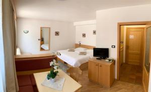 カンピテッロ・ディ・ファッサにあるGarnì Tobiàのベッドとテレビが備わるホテルルームです。