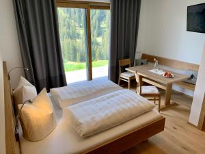 a bedroom with two beds and a table and a window at Ländle Hotel in Damuls