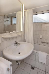 a white bathroom with a sink and a shower at Concorde Hotel Siegen in Siegen