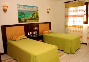 - 2 lits dans une chambre avec des draps verts dans l'établissement Lagoa Eco Village, à Pipa