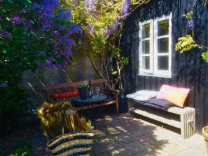 een patio met een tafel, een bank en paarse bloemen bij Strandværelserne in Ebeltoft