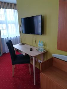 a room with a desk with a tv and a chair at Hotel pod Muzami in Kamień Pomorski