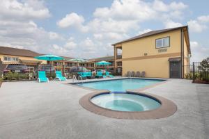 una piscina con sillas y sombrillas en un resort en Days Inn & Suites by Wyndham La Porte, en La Porte