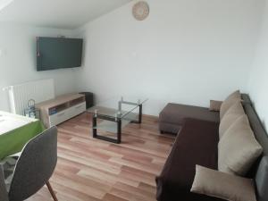a living room with a couch and a table and a tv at Apartman MIG in Solin