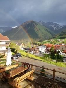 a rainbow over a town with a picnic table and a mountain at Gästehaus Baldauf in Berwang