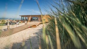 a view of a beach with a bench and a building at California Suite Wenduine in De Haan
