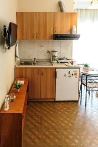 a kitchen with wooden cabinets and a white refrigerator at Mary's Studio Kavala in Kavala