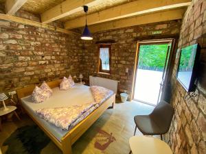 a bedroom with a bed and a stone wall at Holiday park Hajducka cesma in Dubovsko