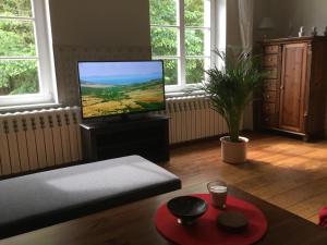 a living room with a flat screen tv and a table at Exklusive Ferienwohnungen im Gutshaus Viezen in Bernitt