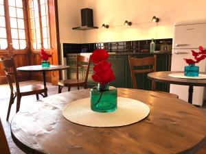 einem Holztisch mit einer Vase mit roten Blumen darauf in der Unterkunft Residenza del Duse in Bologna